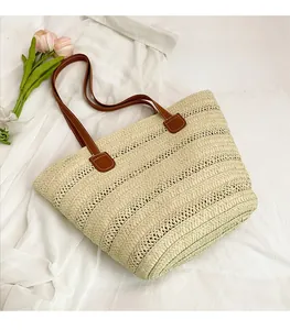 Close-up of the beige woven straw tote bag featuring brown leather handles and neat stitching