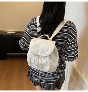 White quilted backpack for women featuring colorful embroidery and drawstring closure