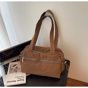 Detail of large dark brown tote bag with dual main zipper compartments and storage pockets