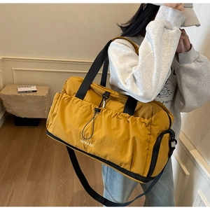 Lifestyle shot of large yellow nylon travel bag with shoulder strap worn by model