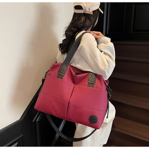 Detailed view of the large rose red travel duffel bag with front pockets and brand patch