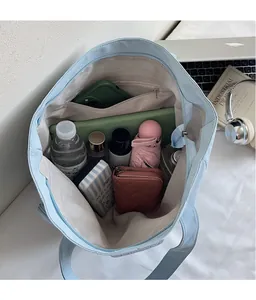 Internal view of spacious light blue tote bag showing laptop, water bottle, and zipper pocket