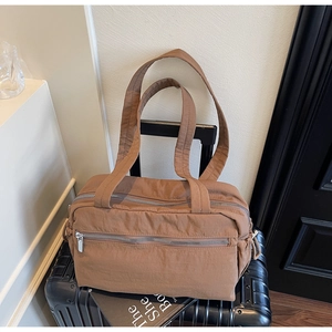 Close-up of brown nylon tote bag with multi-layer zippers on a black suitcase