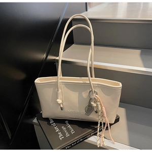 Detail of white faux leather tote bag with lychee texture and decorative tassel