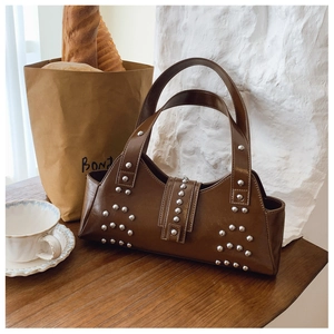 Close-up of vintage brown leather underarm bag featuring decorative silver metal rivets