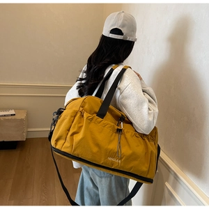 Close-up of mustard yellow travel bag showing drawstring side pocket and durable nylon straps