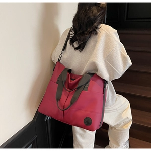 Close-up of waterproof nylon tote bag in deep red with front pockets and broad straps