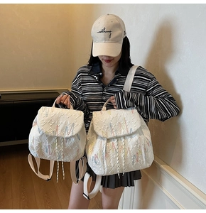 Detail of white quilted backpacks showing wave embroidery and dual-size comparison
