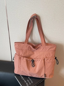 Terracotta nylon tote bag with drawstring pockets on books, perfect for daily commuting