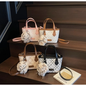 Mini checkerboard tote bags in four colors with plush bunny charms on wooden stairs