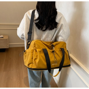 Close-up of yellow large capacity travel bag with multi-pocket design and nylon straps