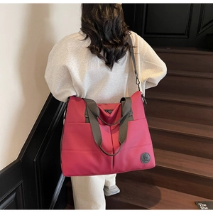 Deep pink large nylon tote bag with grey woven handles shown on person in a modern setting