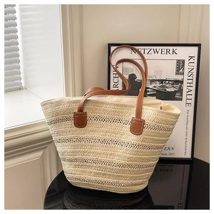 Detailed view of woven straw tote bag texture with reinforced brown leather handles