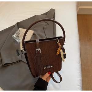 Detail of dark brown bucket bag featuring woven texture and decorative wooden beads