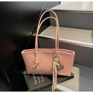 Detailed view of pink tote bag with brand embossing and tennis racket tassel charm