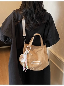 Khaki nylon bucket bag with Banatu logo and capybara charm worn by model