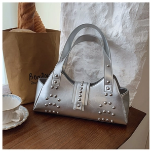 Detail of silver metallic rectangle handbag with geometric silver stud accents on dark wood