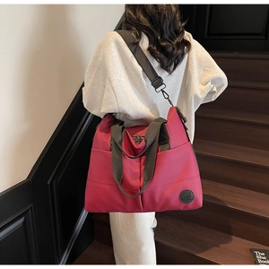 Close-up of durable pink travel tote bag with reinforced handles on wooden stairs