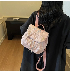 Pink quilted backpack with star pattern embroidery and wavy colorful stitching detail