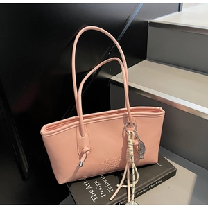 Pink PU leather tote bag with embossed logo and tennis racket charm on a design book