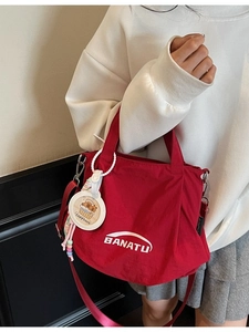 Red canvas tote bag with Banatu logo and Capybara charm shown as a crossbody bag