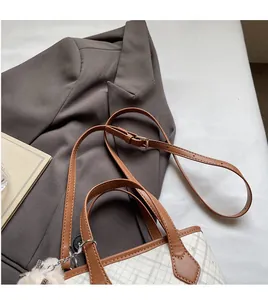 Detail showing checkered tote bag with brown leather handles and a long shoulder strap