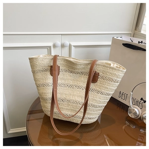 Close-up of woven straw tote bag texture and brown leather shoulder strap on a table