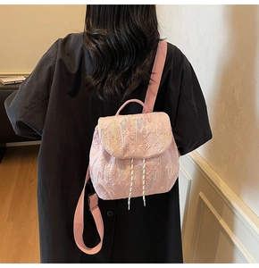 Detail of pink quilted mini backpack with colorful wavy stitching on woman's back