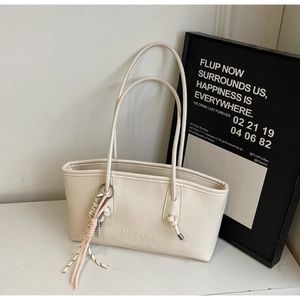 Detail view of cream PU leather tote bag with braided colorful rope charm on the handle