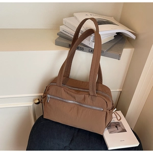 Close-up of brown nylon tote bag with multi-compartment zipper design and shoulder straps