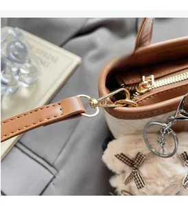 Close-up of beige checkerboard tote bag with golden hardware and plush bear charm