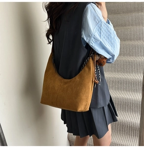 Brown suede hobo bag with braided side tassels and a cute plush bear charm detail