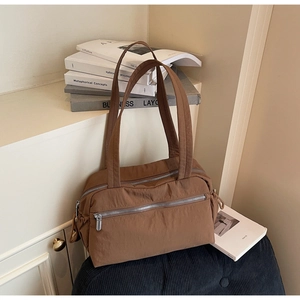 Close-up of brown multi-pocket nylon shoulder bag on a stylish striped indoor cushion