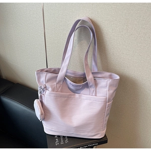 Detail of lavender nylon tote bag featuring a round mini coin purse charm and logo