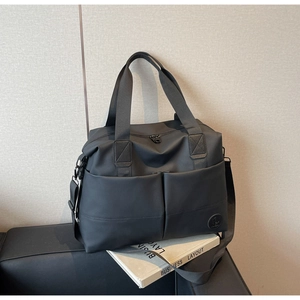 Detailed view of a black waterproof travel duffel bag with sturdy handles and shoulder strap