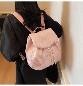Pink quilted backpack with colorful embroidery shown on model for daily commuting