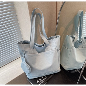 Detail of light blue nylon tote bag with front pocket and round coin purse attachment