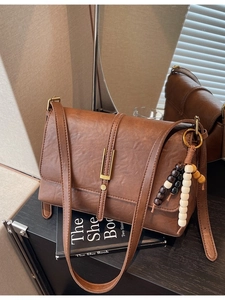 Retro brown leather shoulder bag with gold metal buckle and beaded tassel charm