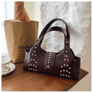 Detail of vintage punk style chocolate leather bag with silver rivets on wooden surface