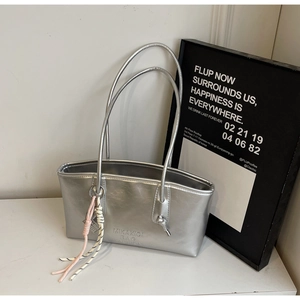 Close-up of a silver leather tote bag featuring modern embossed texture and woven knot detail