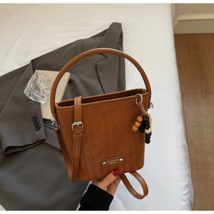 Detail of brown woven texture bucket bag with adjustable strap and wooden bead charm