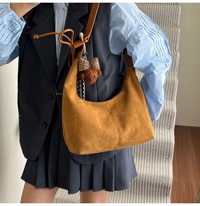 Close-up of brown suede hobo bag with teddy bear pendant on model in vintage style