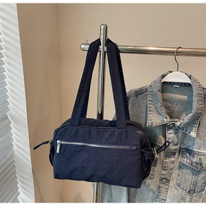 Close-up of a navy blue nylon shoulder bag with silver zipper pocket and drawstring detail