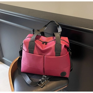 Detail of dark red travel backpack with large front pockets and black webbing handles