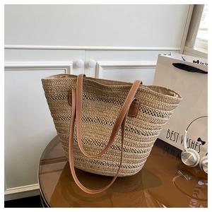 Close-up of woven straw tote bag with brown leather handles and contrast stitching