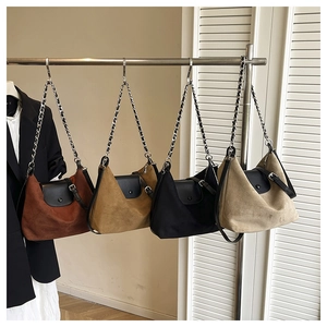 Detail of suede chain tote bags in brick red, tan, black, and beige colors
