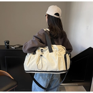 Close-up of off-white travel bag showing side drawstring pocket and adjustable strap