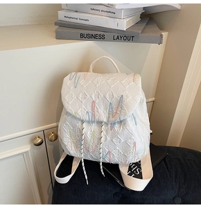Detailed texture of white quilted backpack with colorful wave stitching and E embossed pattern