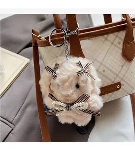 Detail of plush bunny charm with plaid bow and pearls on a stylish tote bag