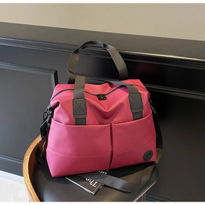Detail of water-resistant deep pink travel bag with black handles on a vintage chair